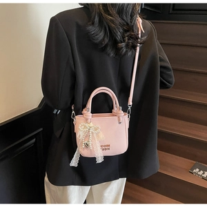 Pink lychee texture bucket bag featuring pearl lace bow charm and metallic brand logo