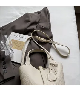 Detail of creamy white bucket bag with litchi texture on fabric near a blazer