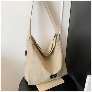 Detail of beige canvas hobo bag texture with brand label and wide shoulder strap
