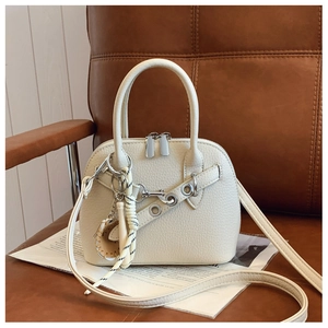 Detail of off-white lychee grain leather shell bag with silver eyelets and woven pendant