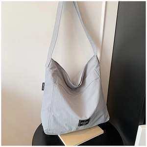 Close-up of lightweight nylon tote bag showing wide shoulder strap and front pocket detail