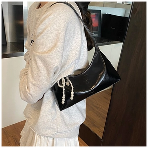 Détail du sac à bandoulière en cuir noir brillant avec pompon perlé et pendentif cœur