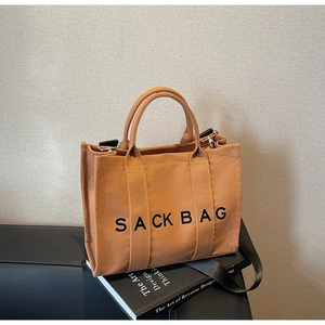 Detail of terracotta canvas sack bag with bold text and detachable black shoulder strap