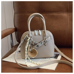 Detailed macro view of apricot textured shell bag with metal eyelets and heart charm