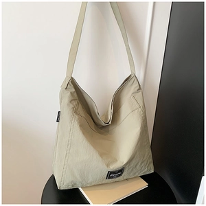 Detail view of high-capacity sage green tote bag showing textured nylon and side logo label