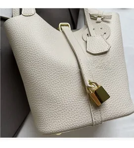 Detail view of cream lychee texture leather bucket bag with gold padlock hardware