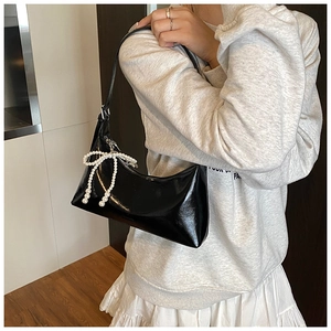 Détail du sac sous l'aisselle en similicuir noir avec élégant nœud en perles et zip