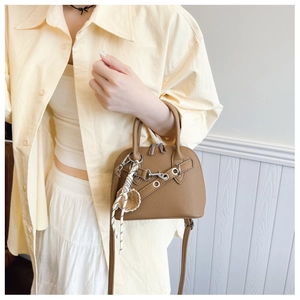 Brown leather shell bag detail with silver hardware and braided rope charm ornament