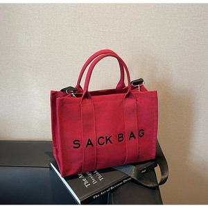 Detail of red canvas tote bag with black Sack Bag text and detachable shoulder strap