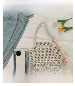 Detail view of beige crochet tote bag with floral scarf showing capacity via gadgets
