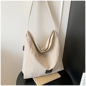 Detail of minimalist cream oversized tote bag showing textured fabric and brand woven label