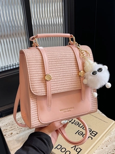 Elegant pink woven leather handbag with double gold buckles and a plush ball charm