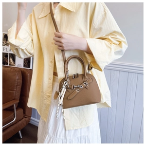 Brown lychee leather shell handbag with horsebit detail and tassel on a female model