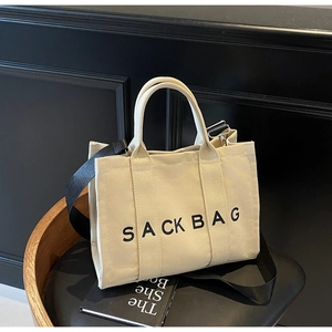 Detailed close-up of a beige canvas tote bag with SACK BAG print on a chair