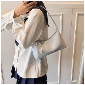 Détail du sac sous l'épaule en cuir bleu clair avec breloque papillon en perles