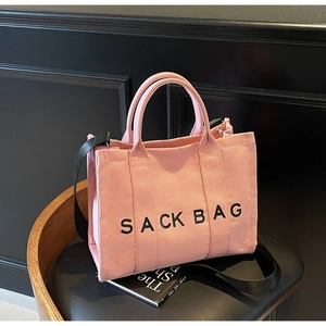 Pink canvas sack bag with wide black shoulder strap and large interior capacity