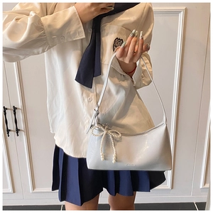 Détail du sac sous l'aisselle en cuir gris brillant avec un charmant nœud perlé