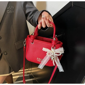 Detail of red lychee pattern bucket bag with lace bow, pearls, and heart charm detail