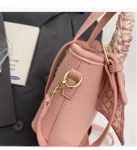 Detail of pink lychee leather bag with gold hardware and decorative silk scarf