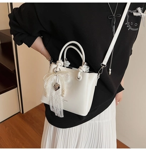 Détail du sac seau blanc avec nœud en dentelle, pendentif cœur et texture en cuir lisse