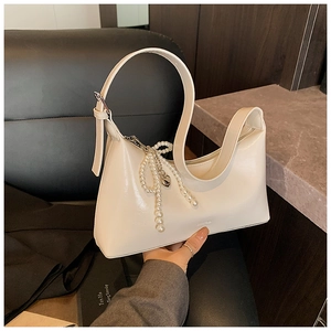 Détail d'un sac hobo en cuir souple blanc avec breloque perle et bandoulière