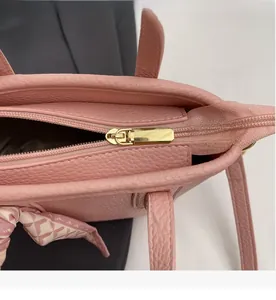 Detail of golden zipper and pink lychee grain leather handle with silk scarf decoration