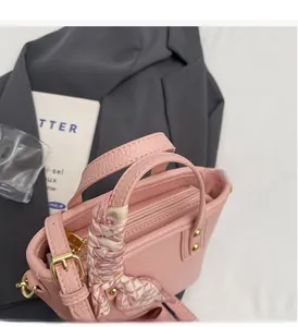 Detail of pink lychee grain leather bucket bag with silk scarf and gold hardware accents
