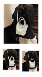 Close-up of white lychee pattern leather bucket bag with gold lock and smiling pendant