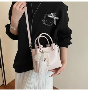 Détail du sac seau rose avec nœud en dentelle, perles et pendentif en forme de cœur