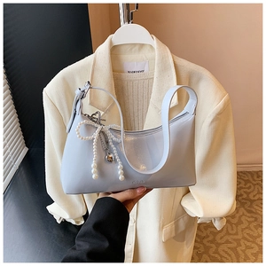 Détail du sac sous le bras en cuir souple bleu clair avec breloque papillon perle