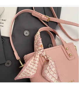Detail of pink lychee leather handbag with silk scarf wrapped handle and gold rivets