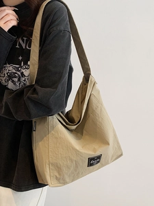 Large khaki nylon tote bag for women showing a casual shoulder style on a model