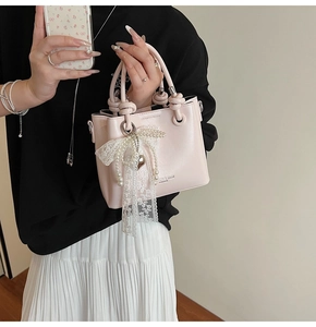 Vue détaillée d'un sac seau rose avec poignée nouée et breloque en dentelle perlée