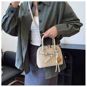 Detail of beige shell handbag with premium lychee grain leather and glove charm