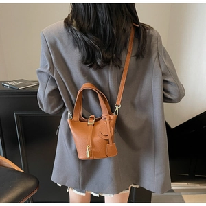Detailed macro view of brown lychee grain leather bucket bag with metal lock and smile charm