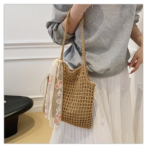 Close-up of woven straw beach bag featuring hollow-out patterns and floral lace scarf