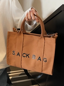 Brown canvas tote bag with SACK BAG print featuring top handles and black shoulder strap