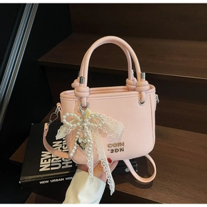Detail of pink litchi grain bucket bag with lace pearl bow and heart charm