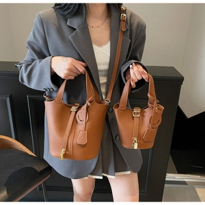 Brown lychee leather bucket bags set with gold padlock detail on a grey suit model