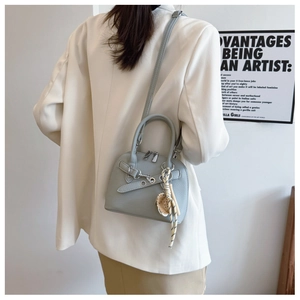 Close-up of light blue pebbled leather shell bag with silver hardware and baseball charm