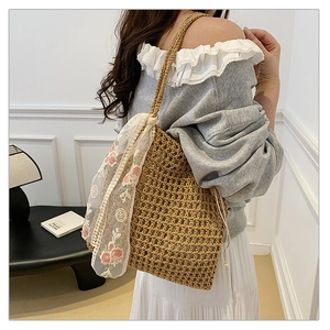 Detail of hand-woven straw shoulder bag with floral lace ribbon and drawstring lining