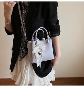 Détail du sac seau lilas plissé avec nœud en dentelle et breloque en forme de cœur