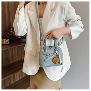 Detail of light grey shell bag in pebbled leather with embroidery charm accessory