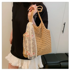 Detailed close-up of handmade straw tote bag with floral embroidery and white lace trim