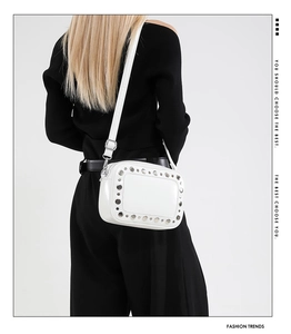 Dettaglio borsa bianca con borchie argentate indossata da modella su vestito nero