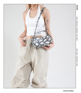 Chic snakeskin print crescent bag worn by model with adjustable metal buckle strap
