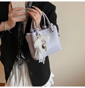 Détail du mini sac seau lavande avec pendentif en perles et nœud en dentelle