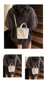 Detail of white lychee pattern bucket bag with decorative silk ribbon on top handle