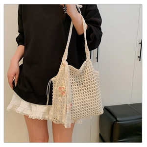 Detail of hollow-out woven tote bag featuring floral embroidery lace ribbon accessory