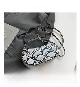 Flat lay of a snakeskin print baguette bag next to a blazer and a fashion book
